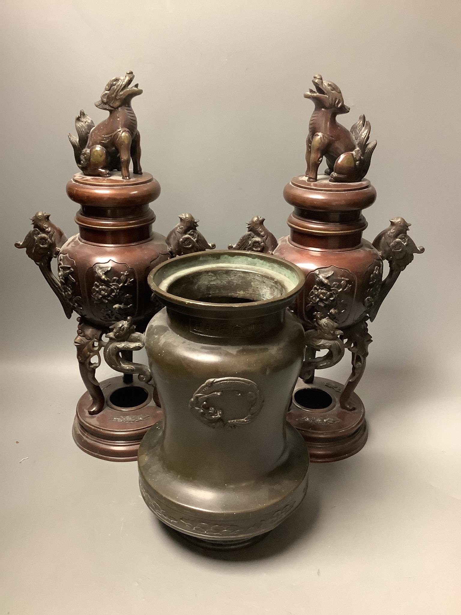A pair of Japanese bronze vases and covers, 41 cm high and a Japanese two handled vase, 26 cm high, all Meiji period